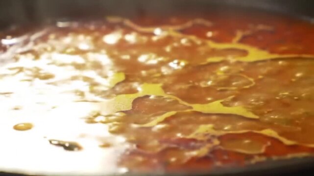 Close up shot of bubbling orange liquid showing a thick and viscous texture surface