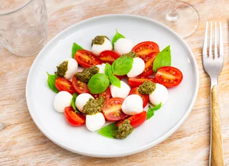 Caprese salad with basil and pesto sauce served on plate. Traditional Italian salad. © JackF