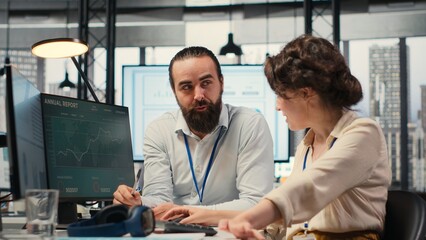 Business partners engaging in a discussion about financial forecasting and data insights, cheerful teamwork in a modern workspace. Man and woman ensuring goals achievement. Camera B.