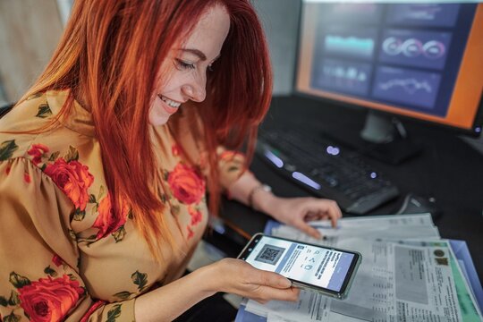 Young businesswoman scanning qr code with smartphone in office