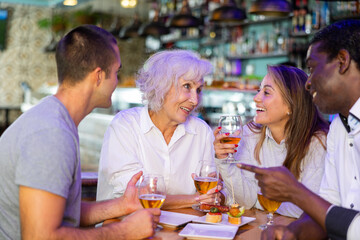Friendly joyful family celebrating meeting holding glasses with beer in cosy bar. Main focus right in center