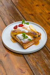 Delicious gourmet breakfast featuring French toast, caramelized bananas, and fresh berries on a plate
