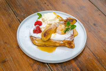 Delicious gourmet French toast with caramelized bananas and fresh strawberries ready to eat