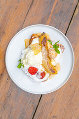 Delicious dessert of caramelized banana, strawberries, and ice cream on a white plate