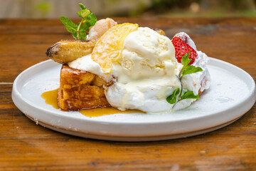 Delicious French toast dessert with ice cream, fruit, and syrup on a white plate, ready to eat!