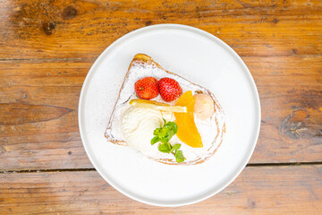 Delicious gourmet dessert of French toast, fresh fruit, and ice cream on a white plate
