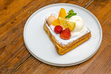 Delectable dessert with fresh fruit, ice cream, and powdered sugar served on a white plate