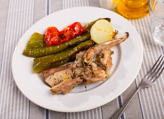 Appetizing fried rabbit served on plate with garnish of peppers and onions