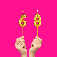 Birthday on a fuchsia background with the number 68 - Hands holding number-shaped candles