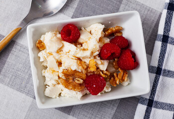 Healthy breakfast, light and hearty dietary snack - cottage cheese with honey, walnut and some raspberry.