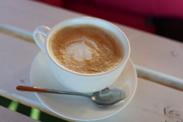 Close-up of a creamy latte with an exquisite foam pattern in a white cup on a wooden table, creating a cozy café atmosphere. Perfect for beverage branding, morning rituals, or lifestyle content.
