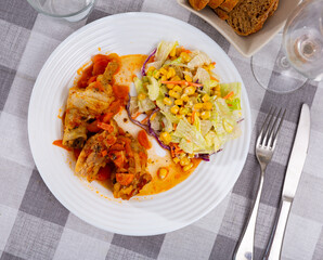 Baked chicken pieces under sauce with carrot and mixed vegetables served in a plate