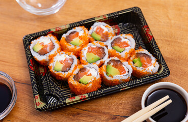California roll masago caviar with salmon, avocado and cheese with bowl of soy sauce