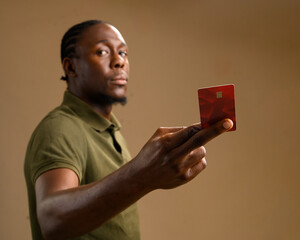 African man in green polo shirt holding a red debit card towards the camera, concept of digital...