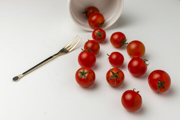 Top view flat lay of fresh ripe cherry tomatoes scattered on a white background. Concept for healthy eating, organic food, cooking ingredients, and nutrition with copy space.