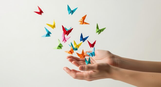Hands releasing a flock of colorful origami butterflies into the air, symbolizing freedom and creativity, isolated on white background