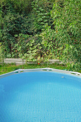 Frame pool with clean water in the garden on a background of plants.