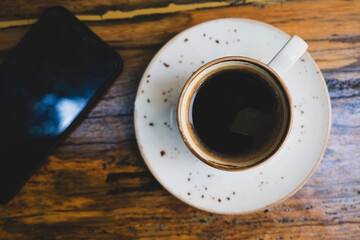Morning Coffee and Smartphone on Desk. Cup of Coffee and Smartphone on Wooden Table. Coffee Break with Mobile Phone.