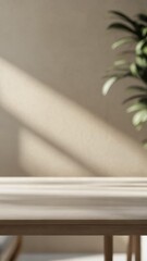 Light wooden table with soft plant shadow on beige wall, indoor minimalist interior, natural sunlight, copy space