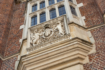 Royal emblem under a window ledge in Hampton Court Palace, England.
Two gargoyles protecting a royal shield that is part of a coat of arms.