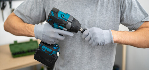 Mechanic holds an impact wrench, adjusting the tool before starting automotive repairs in a...
