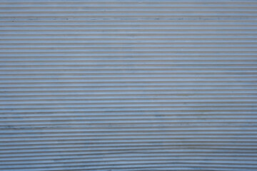 White metallic rolling door backdrop. White metal shutter background. Closed shop shutter surface texture. Steel roller shutter pattern.