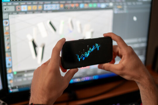 A person shows a smartphone screen with a stock graph while a larger digital display illustrates market trends behind them. The setting highlights financial analysis. - Powered by Adobe