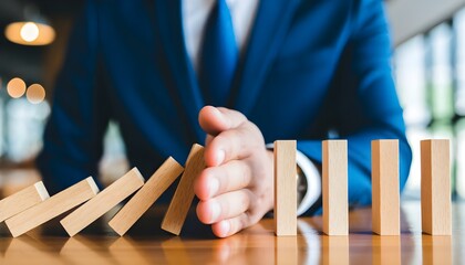 Businessman's hand stopping the domino effect, a powerful metaphor for risk management, crisis intervention, and strategic business solutions