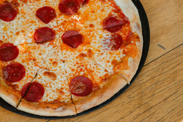Tasty Italian pepperoni pizza on wood table. Pepperoni pizza on rustic background. Freshly baked pepperoni pizza on wood surface.