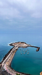 Obraz premium Vertical photo of seascape view of small boats docking around half island called Ex-Island alacrán in Arica, Parinacota Region in Chile in South America.