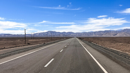 Straight paved road going through desert landscape in Atacama, region Tarapacá in Chile. Traveling, driving, road trip, tourism, vacation, transportation