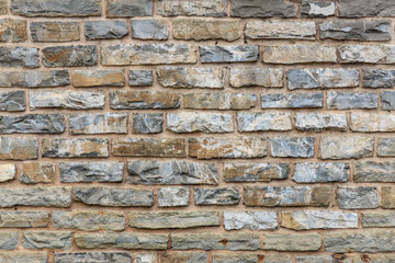 Textured gray and beige brick wall with rough stonework pattern