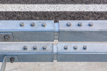Close-up of metal highway guardrail with bolts on asphalt road