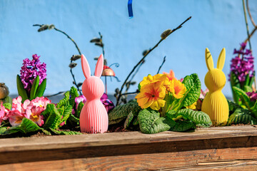 A wooden shelf with a bunch of flowers and three small rabbits