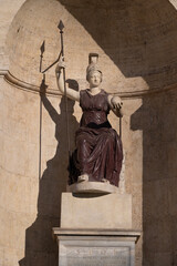 The seated statue of Dea Roma (Goddess Roma), composed of red porphyry and white marble, in the central niche of the Palazzo Senatorio fountain on Rome's Capitoline Hill, under strong sunlight, Rome