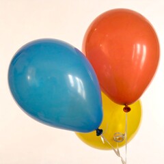 Three colorful balloons, blue, red-orange, and yellow, against a plain background