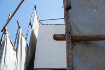 足場丸太を番線で固定して遮蔽シートを掛けた様子