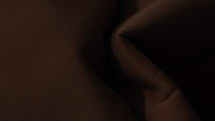 Dark cocoa folds background on smooth woven textile surface, abstract fabric texture with soft creases and moody lighting depth