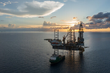 Fototapeta premium Aerial view of offshore jack up rig and offshore platform during sunset for oil and gas exploration and production.