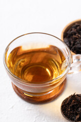 Black tea in cup glass with dried tea leaves on white background, Healthy herbal hot drink
