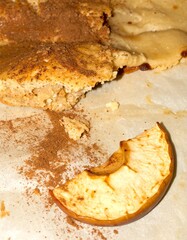 Warm cinnamon apple crumble slice with baked fruit and spice dust on parchment paper