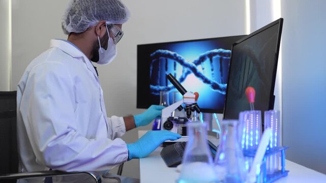 A geneticist performs microscopic analysis of a cellular sample, cross-referencing observations with genomic data displayed on a bioinformatics workstation in a biotech lab.