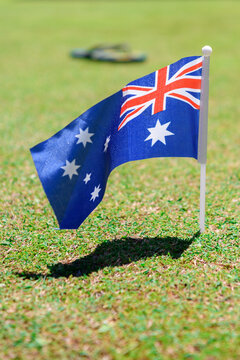 An Australian flag in the foreground with a thong blurred in the background - vertical