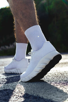 Persona trotando con tenis blancos y calcetas blancas en pista de tart&aacute;n al aire libre