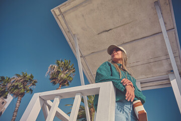 Female lifeguard scanning the beach for potential hazards from her elevated lifeguard station on a sunny summer day