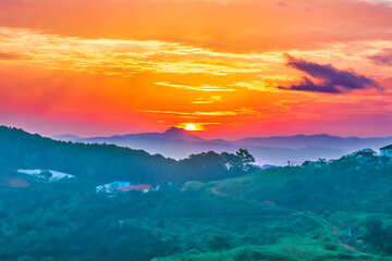 Amazing mountain landscape at sunrise, scenic view of silhouettes of the mountains range, fantastic colorful sky with clouds and rising sun, outdoor travel background suitable for wallpaper