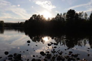 Beautiful reflection of trees in the water on a vast river in summer or in autumn. Riverside at the sunset and peaceful landscape. Zen atmosphere and summer or autumn calendar. Calm water.