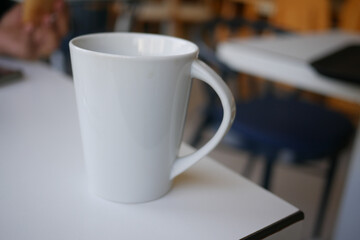 Simple white mug on a table in a cozy cafe setting