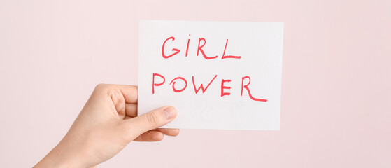Female hand holding paper sheet with text GIRL POWER on color background. Concept of feminism