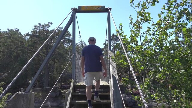 Stendorren, Sweden A man walks over a pedestrian bridge in the Stendorren Nature Reserve to a rocky island in the Baltic Sea.